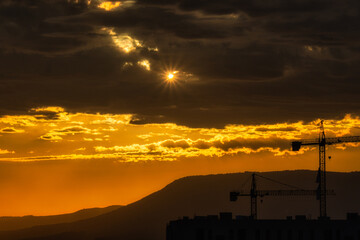 Sunset silhouette of cranes and cityscape