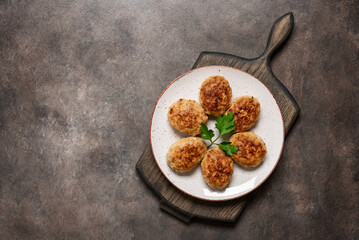 Fried cutlets in a plate on a wooden board, dark background. Top view, flat lay, copy space.