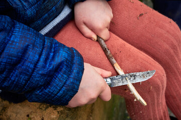 Petite fille découpant du bois avec un couteau Opinel