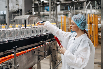 Female worker in protective workwear working in medical supplies research and production factory and checking canisters of distilled water before shipment. Inspection quality control.
