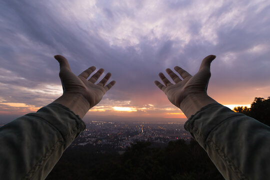 man raised her hands above her head to ask for mercy from God in accordance with her belief in God in Christianity. man raising both hands to ask for blessings from God according to beliefs