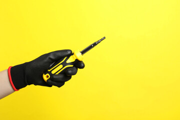Woman holding screwdriver on yellow background, closeup. Space for text