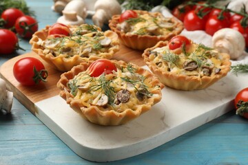 Tasty tartlets with cheese, tomatoes, mushrooms and dill on turquoise wooden table, closeup