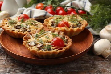 Tasty tartlets with cheese, tomatoes, mushrooms and dill on wooden rustic table, closeup