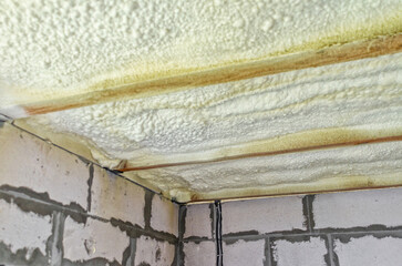 Insulation of the ceiling in house with polyurethane foam. Insulating foam between wooden beams