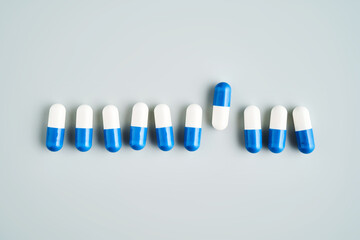 A row of white and blue pills on a blue background.