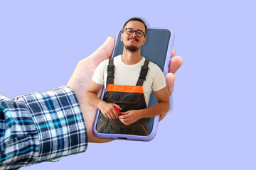 Male hand holding purple phone with portrait of young builder. Repairman or husband on hour...