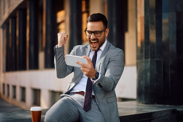 Cheerful businessman celebrating good news while reading text message on cell phone.