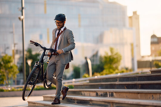 Happy entrepreneur carrying his bicycle down stairs.