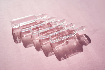 Ampoules for injection with medicines on a pink background.