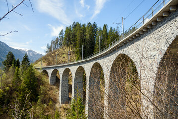 Low angle view of a single-track limestone railway viaduct in the Swiss Alps on a sunny spring day