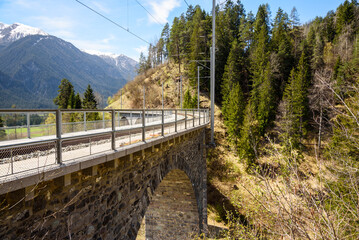 Deserted single-track railway viaduct in the Swiss Alps on a sunny spring day