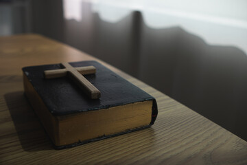 cross is placed on the Bible after prayer to God, which is religious ritual of Christianity and...