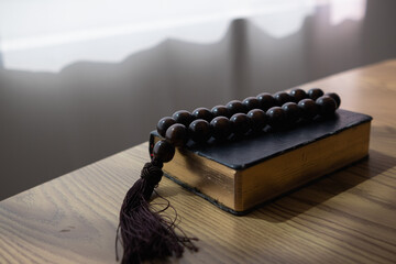 Bible and rosary placed on a wooden table after praying to God which is a Christian religious...
