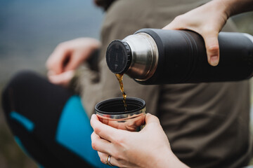 Pouring liquid from thermos to cup, using finger gesture