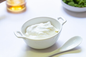 Greek yogurt and wolffia globosa in ceramic bowl isolated on white table background. Wolffia is the...