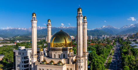 A mosque in the Kazakh city of Almaty against the backdrop of a mountain range on a spring day