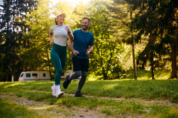 Happy couple of athletes running in nature.