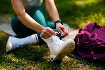 Close up of athletic woman tying shoelace in the park.