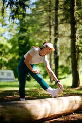 Happy sportswoman doing stretching exercises while working out in nature.