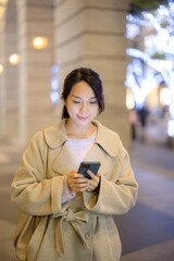 Fototapeta premium Woman use on mobile phone and walk along the street at night