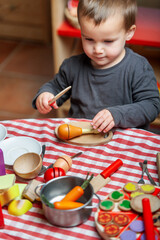 Little boy playing at cooking with wooden toys. Symbolic and imaginative play