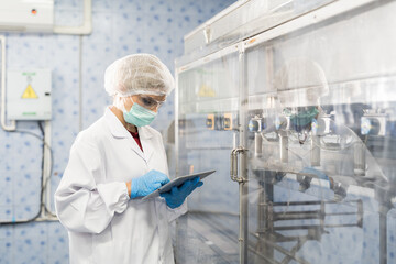 Female worker produces inspecting quality of plastic water tank on conveyor belt in drinking water...