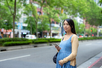 Pregnant woman use cellphone to order taxi in the city