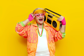 funny crazy granny in hipster clothes listening to music on tape recorder and singing on yellow...