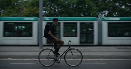 Side shot of young commuter ride a bicycle on a bike lane without holding on the handlebars. Office worker or student on the way to school or work. Space for text. 