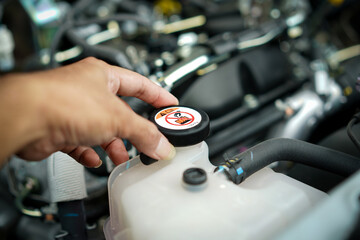 Hands man auto mechanic opening the car's radiator cap for checking coolant water level in radiator...