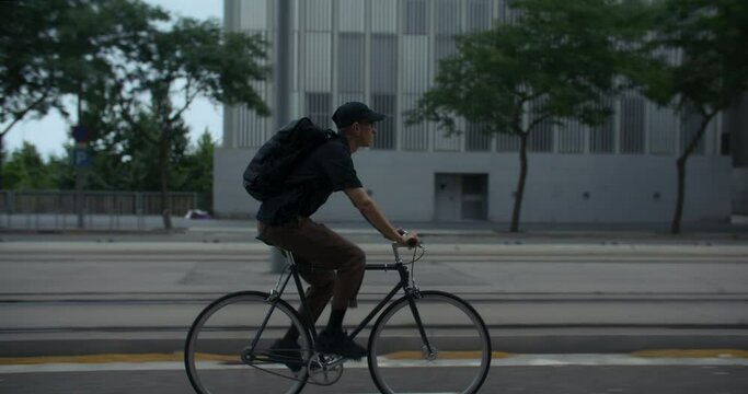 Office worker or student ride bicycle on bike lane to work or school. Young man reaching his destination. Ecological lifestyle. Side shot.  - Powered by Adobe