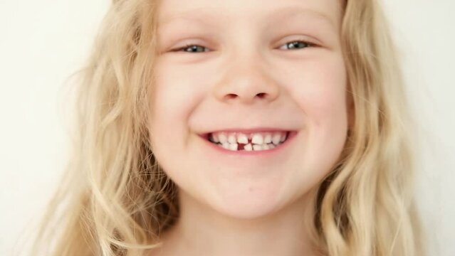 portrait Blonde haired curly caucasian baby girl without first milk tooth in mouth. stomatology. kid loses his first tooth. children Toothless smile