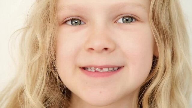 portrait Blonde haired curly caucasian baby girl without first milk tooth in mouth. stomatology. kid loses his first tooth. children Toothless smile