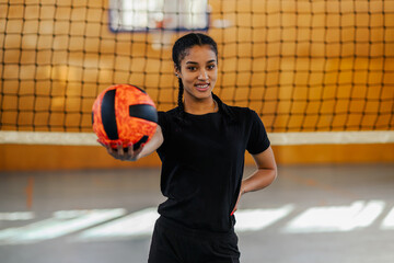 Portrait of a diverse young female volleyball player holding a ball in her hand