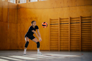 Multiracial young female volleyball player bumping a ball during a training