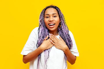 shocked african american woman with colored dreadlocks surprised and looking at camera on yellow...