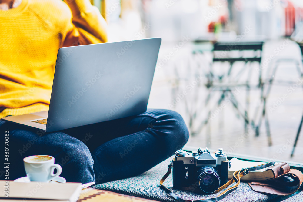 Poster bearded man talking on smartphone while sitting with modern laptop computer and vintage camera in co