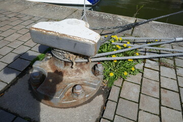 Sturdy metal mooring bollard with lines attached in harbor