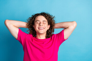 Portrait of satisfied dreamy man with curly hairstyle piercing wear pink shirt hold hands behind...