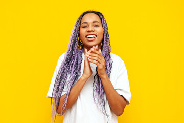 cheerful african american woman with colored dreadlocks applauding and congratulating on yellow...