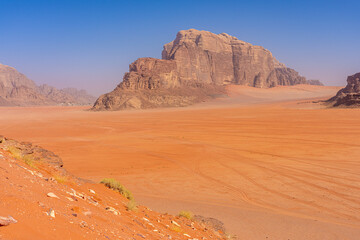 Majestic Desert Valley in Wadi Rum, Jordan: Expansive Red Sands and Towering Sandstone Cliffs Under Clear Blue Sky