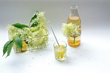 A glass and bottle of homemade organic elder lemonade with flowers and  lemon 