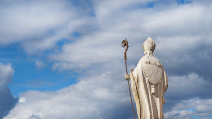 Christian Religion and Spirituality. Bishop or Pope ancient statue with crosier and mitre against...