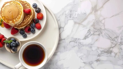 Elegant breakfast composition with stacked pancakes, assorted berries, and a cup of tea, set on a pristine white marbled background. Banner with copy space