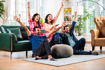Asian Indian young married couple friends spending leisure time watching TV at home together