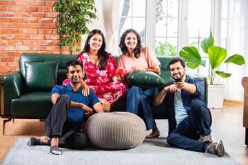 Asian Indian young married couple friends spending leisure time watching TV at home together