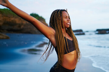 Afro positive american young woman in tracksuit stretching hands up during morning warm-up on...