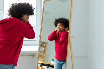 Love yourself. Beautiful young smiling african american woman dancing touching curly hair enjoying...