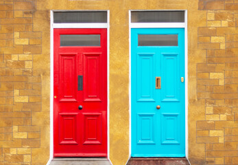 two blue and red doors in yellow brick wall, street facade